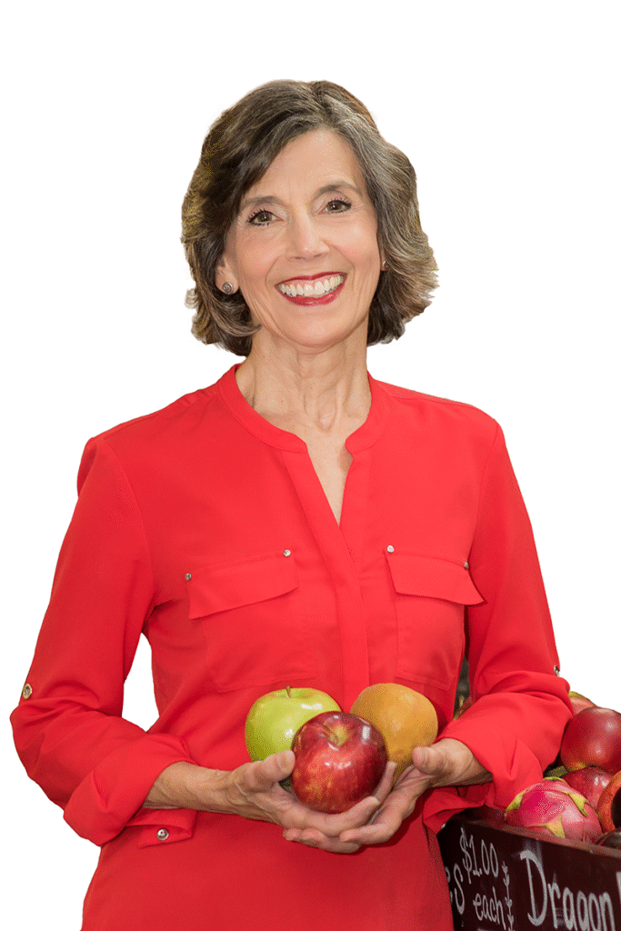 Woman in red blouse holding apples and smiling.